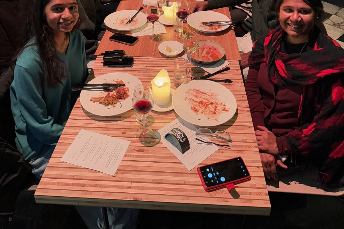 Lakshmee and her entire family along with Chef Seppe Nobels and Tourism Flanders staff member Greet Vandenrijt seated at a long banquet dinner table. They’re all smiles for the camera.
